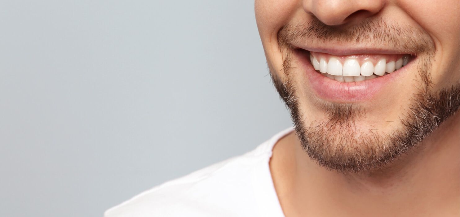 Ein Mann lächelt mit weißen Zähnen in die Kamera.