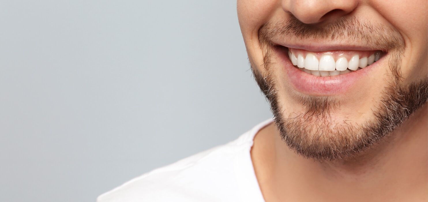 Ein Mann lächelt mit weißen Zähnen in die Kamera.